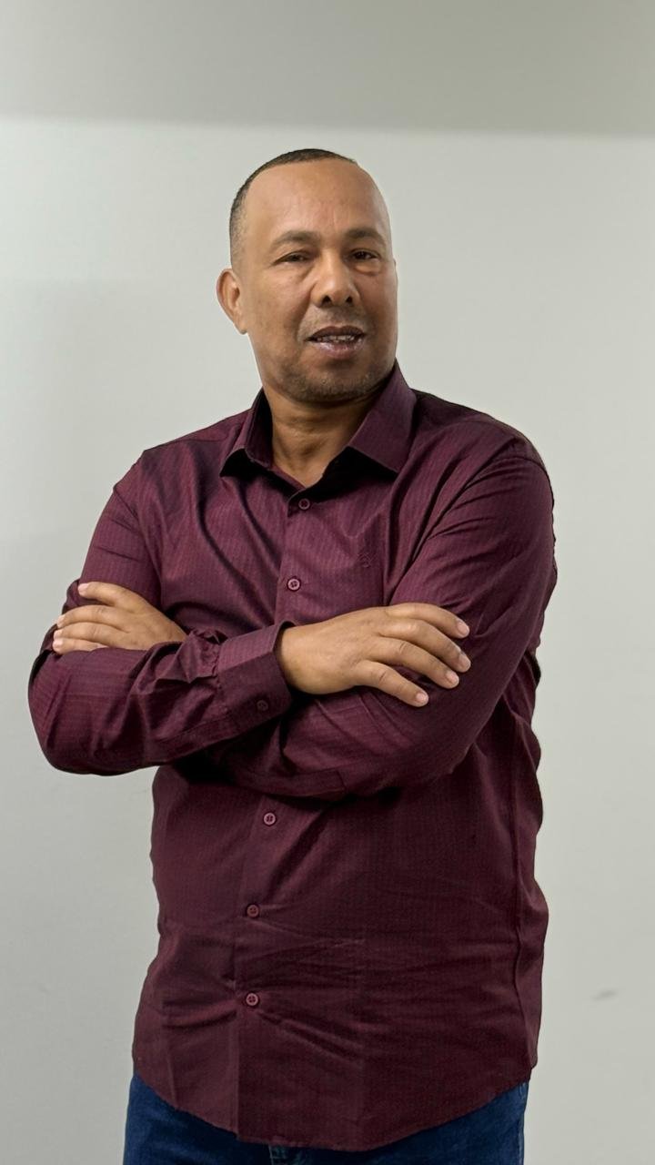 Retrato de Deraldo Rosa com camisa vinho e braços cruzados